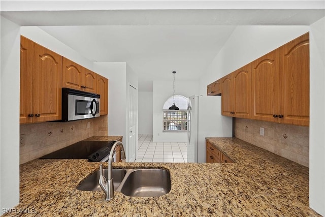 kitchen with white refrigerator, tasteful backsplash, sink, hanging light fixtures, and light tile patterned floors