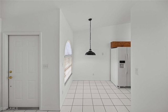 kitchen with pendant lighting, white fridge with ice dispenser, and light tile patterned floors