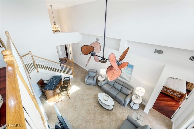 living room with tile patterned flooring, a towering ceiling, and ceiling fan with notable chandelier