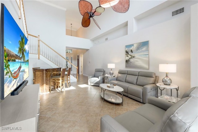 living room with ceiling fan, a towering ceiling, and light tile patterned floors