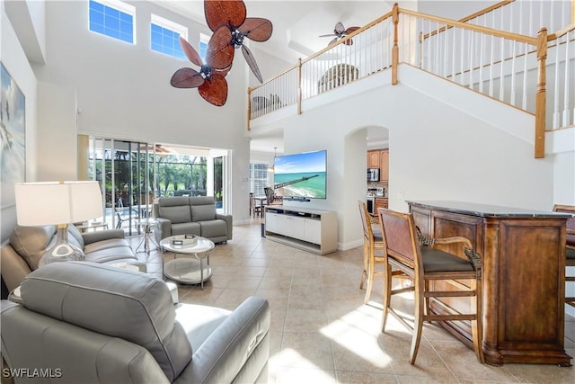 living room featuring ceiling fan, light tile patterned flooring, and a high ceiling