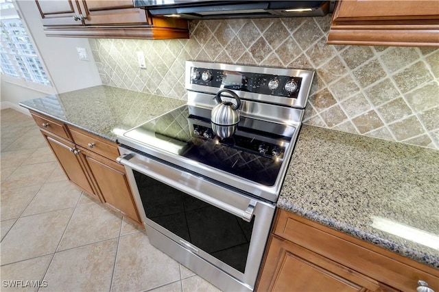 kitchen featuring stone counters, decorative backsplash, light tile patterned floors, and stainless steel range with electric cooktop