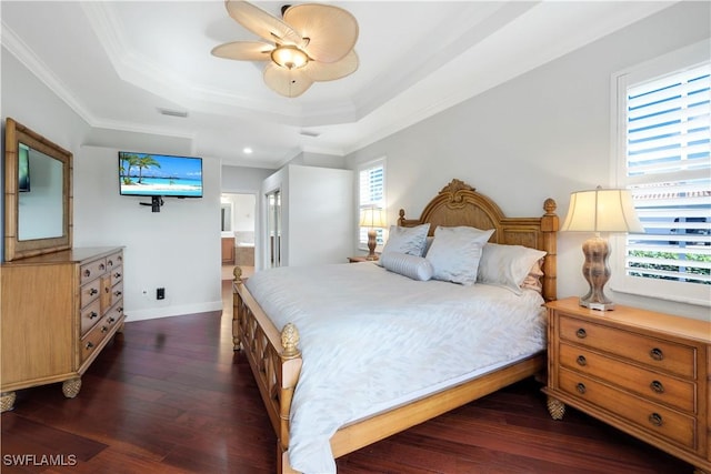 bedroom with connected bathroom, ceiling fan, dark wood-type flooring, a raised ceiling, and ornamental molding