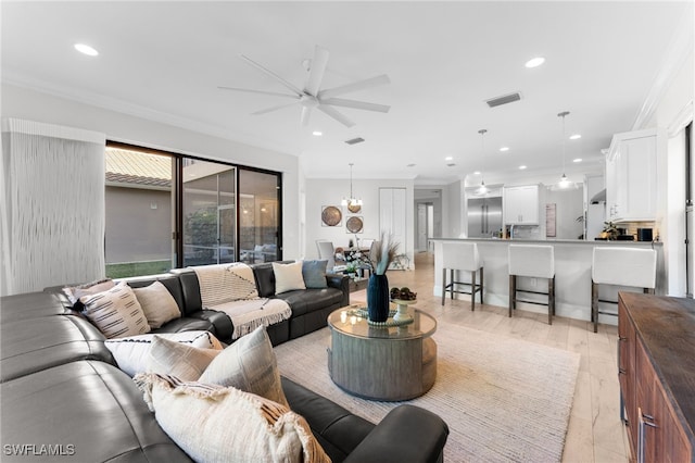 living room with crown molding, light hardwood / wood-style flooring, and ceiling fan