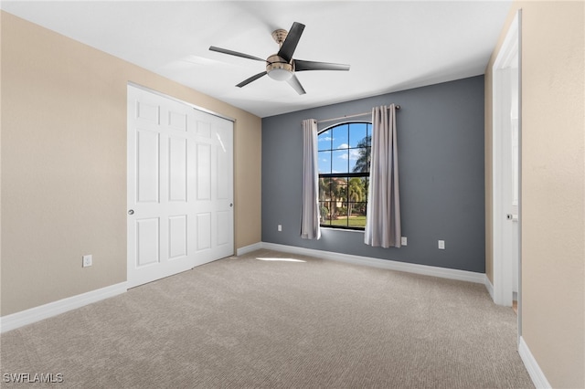 unfurnished bedroom with ceiling fan, light carpet, and a closet