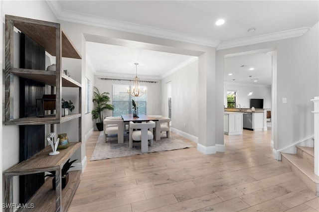 dining room with crown molding, light hardwood / wood-style flooring, sink, and a notable chandelier