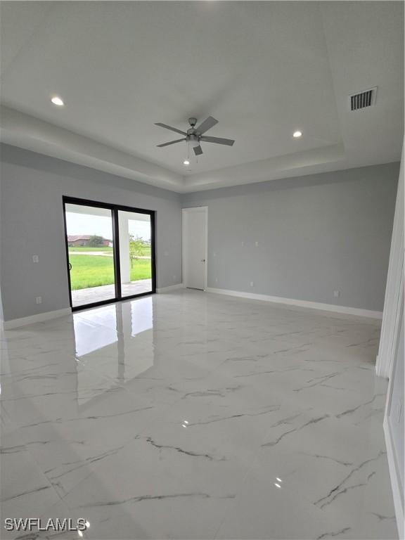 spare room featuring ceiling fan and a tray ceiling