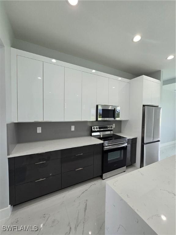 kitchen with white cabinets, light stone countertops, and appliances with stainless steel finishes