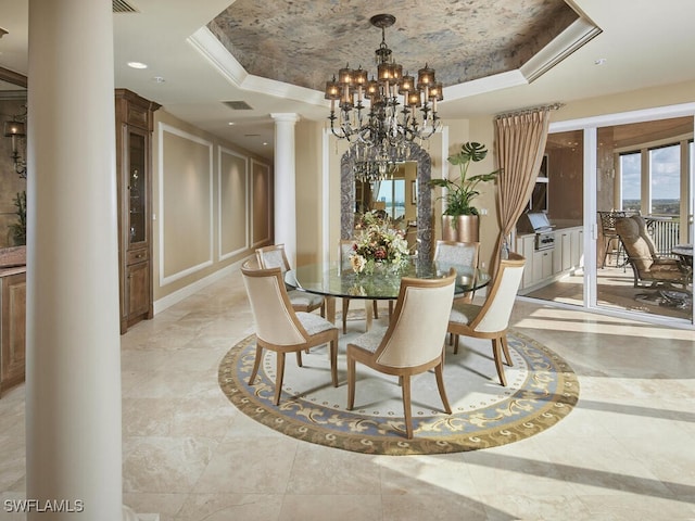 dining room with ornamental molding, a raised ceiling, a chandelier, and decorative columns