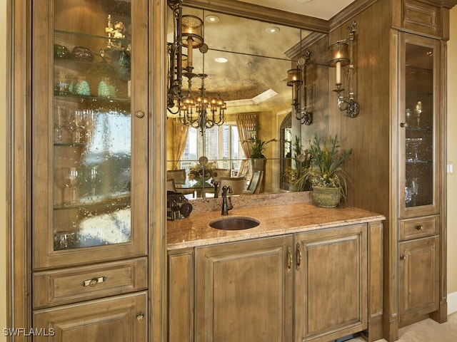 bar featuring sink, a chandelier, and light stone counters