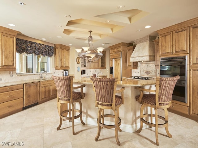 kitchen featuring a center island, custom range hood, pendant lighting, paneled fridge, and a tray ceiling