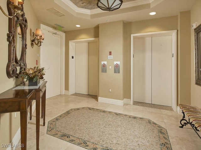 tiled entrance foyer featuring elevator, crown molding, and a tray ceiling