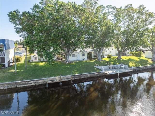 view of dock with a yard and a water view