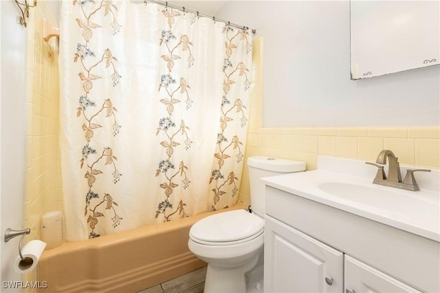 full bathroom with tile patterned floors, shower / bath combination with curtain, toilet, vanity, and tile walls