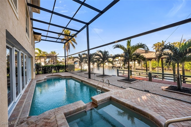 view of swimming pool featuring an in ground hot tub, a water view, glass enclosure, and a patio area