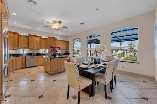 kitchen with dishwasher, a kitchen island, light tile patterned floors, and ceiling fan