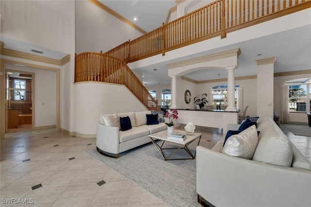 tiled living room featuring crown molding, a towering ceiling, plenty of natural light, and ornate columns