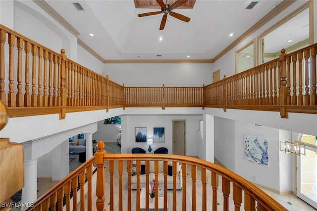 hall featuring an inviting chandelier, ornamental molding, decorative columns, and a high ceiling