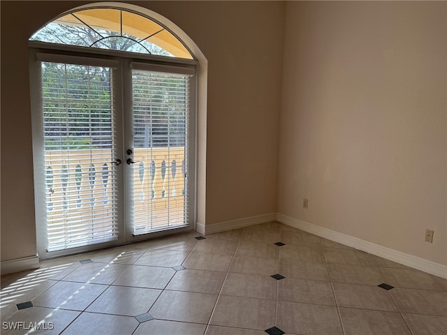 tiled empty room featuring french doors