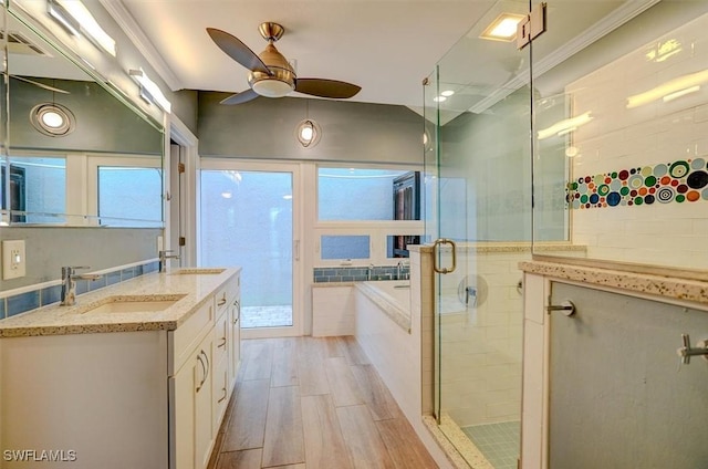 bathroom with hardwood / wood-style floors, ceiling fan, plus walk in shower, ornamental molding, and vanity