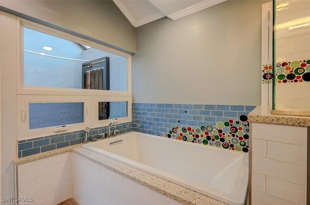 bathroom with ornamental molding and tiled bath