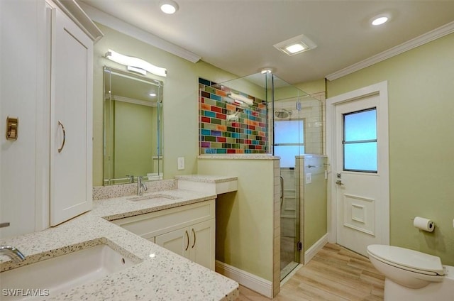 bathroom with vanity, wood-type flooring, ornamental molding, a shower with shower door, and toilet