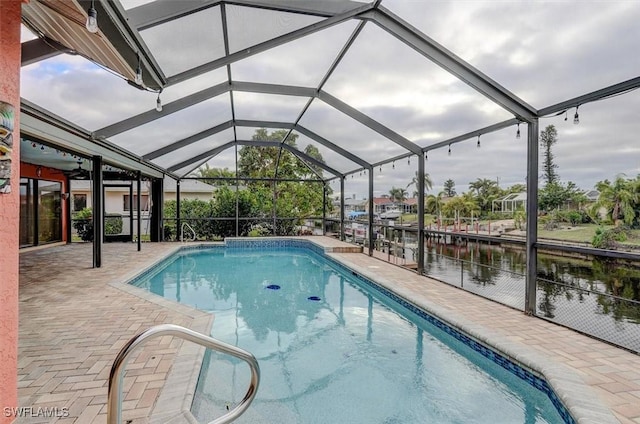 view of swimming pool with a water view, a lanai, and a patio area