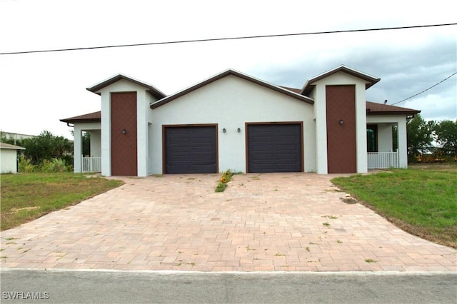 view of front facade featuring decorative driveway, an attached garage, a front yard, and stucco siding