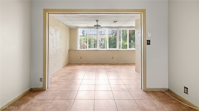 tiled empty room featuring a drop ceiling and ceiling fan