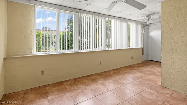 tiled spare room featuring a drop ceiling and ceiling fan