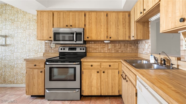 kitchen with backsplash, sink, light tile patterned floors, and stainless steel appliances