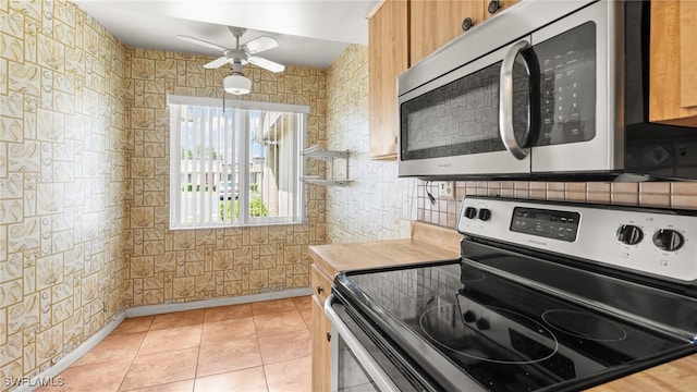 kitchen with ceiling fan, butcher block counters, light tile patterned floors, and stainless steel appliances