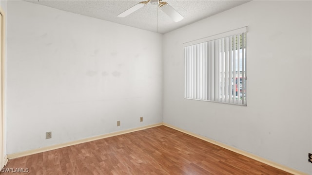 empty room with ceiling fan, wood-type flooring, and a textured ceiling