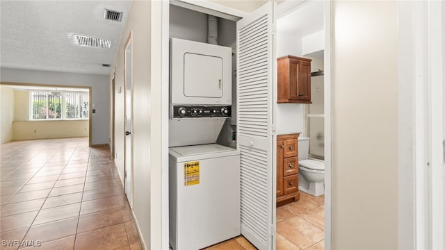 washroom featuring light tile patterned floors, a textured ceiling, and stacked washer / dryer