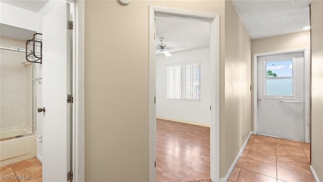 hallway featuring a textured ceiling and light tile patterned flooring