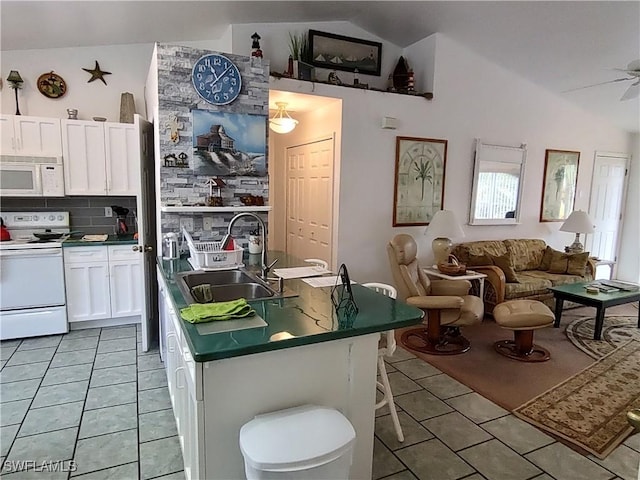 kitchen with white cabinets, white appliances, vaulted ceiling, and sink