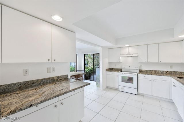 kitchen featuring a tray ceiling, light tile patterned floors, electric range, dark stone countertops, and white cabinets