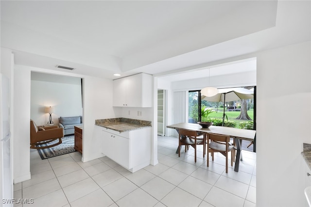 kitchen featuring a raised ceiling, light tile patterned flooring, white cabinets, and pendant lighting