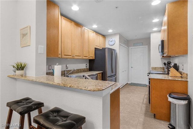 kitchen with appliances with stainless steel finishes, sink, a kitchen breakfast bar, and kitchen peninsula