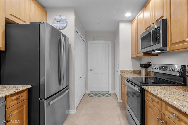 kitchen featuring light stone countertops, appliances with stainless steel finishes, and light tile patterned flooring