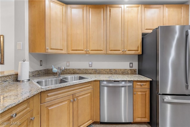 kitchen with light stone countertops, appliances with stainless steel finishes, sink, and light brown cabinetry