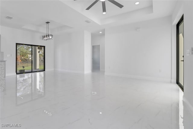 empty room with ceiling fan and a raised ceiling