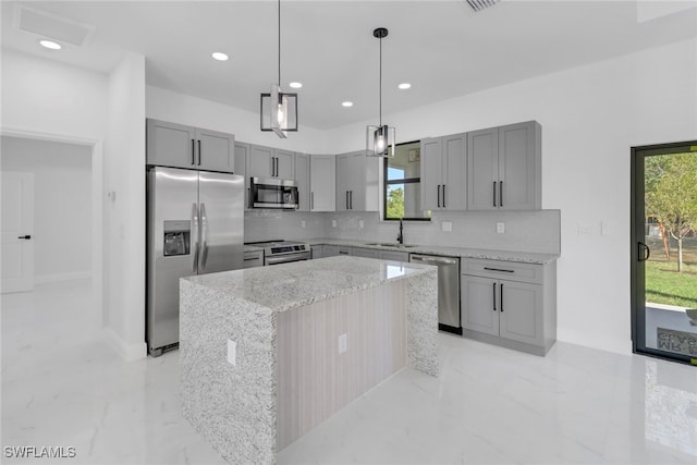 kitchen with pendant lighting, gray cabinetry, a center island, light stone counters, and stainless steel appliances