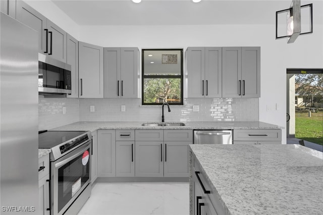 kitchen with tasteful backsplash, light stone countertops, sink, and stainless steel appliances