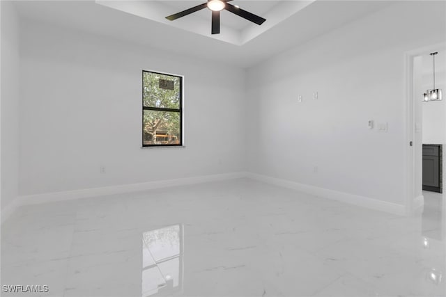 empty room featuring a tray ceiling and ceiling fan