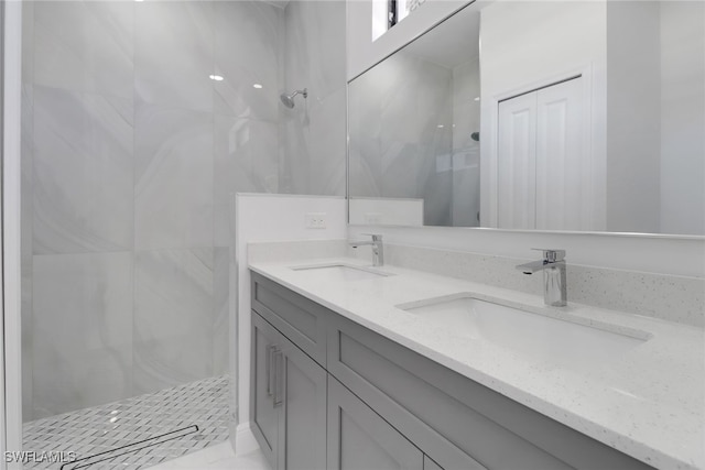 bathroom with a tile shower and vanity