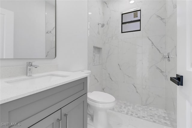 bathroom with vanity, toilet, and a tile shower