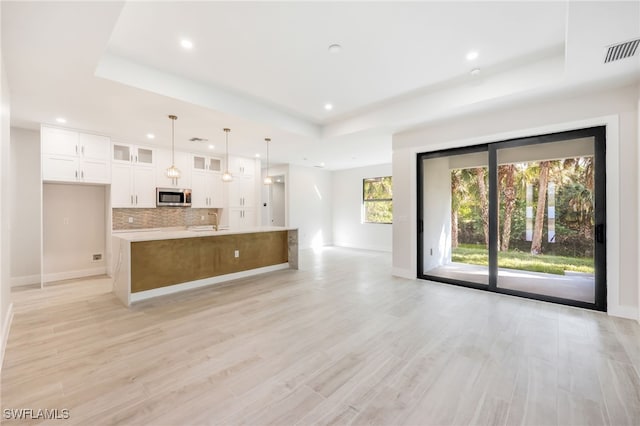 unfurnished living room with a tray ceiling and light hardwood / wood-style floors