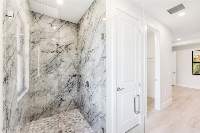 bathroom featuring hardwood / wood-style flooring and tiled shower