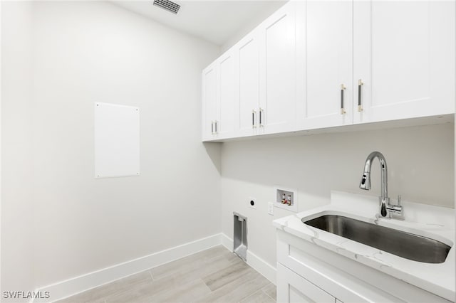 washroom with cabinets, hookup for a washing machine, hookup for an electric dryer, sink, and light hardwood / wood-style floors